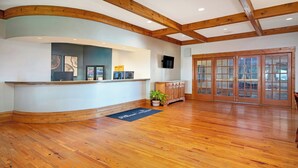 A reception area with a wooden reception desk, a television, and a large glass door entrance. - WorldMark Galena (Hanover)