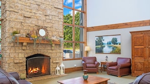 A stone fireplace, leather sofas, a wooden coffee table, and a painting of a landscape. - WorldMark Galena (Hanover)