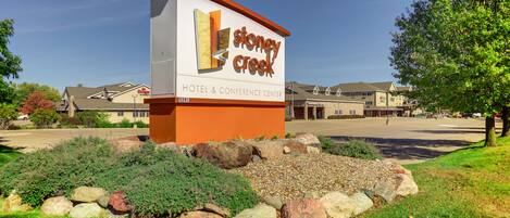 A hotel sign with the name "Stoney Creek Hotel & Conference Center" and a parking lot in the background.