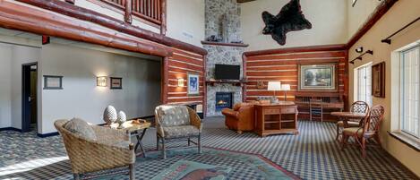A spacious living area with a fireplace, wooden furniture, and a checkered carpet.