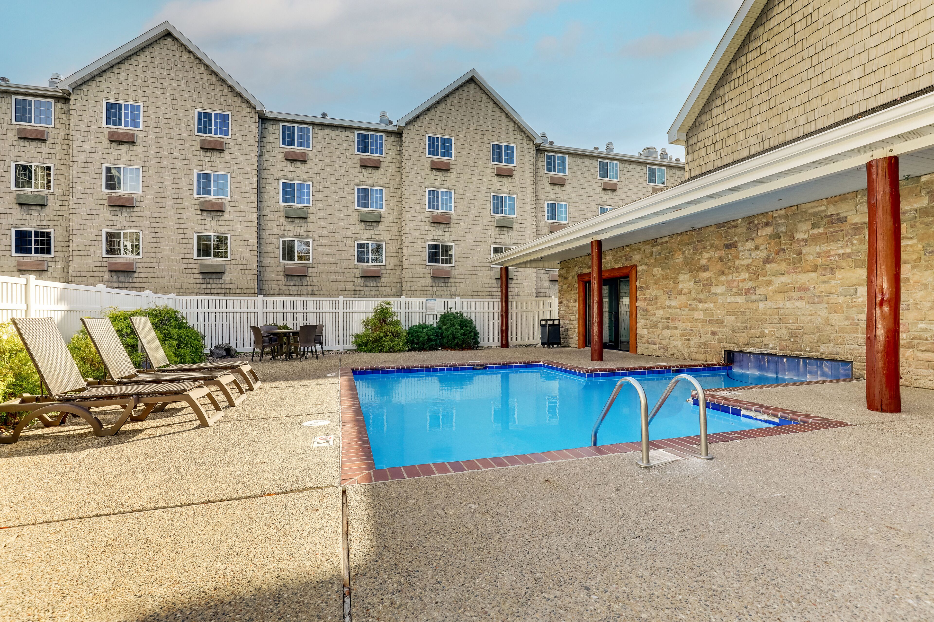 A swimming pool with lounge chairs and a building in the background.