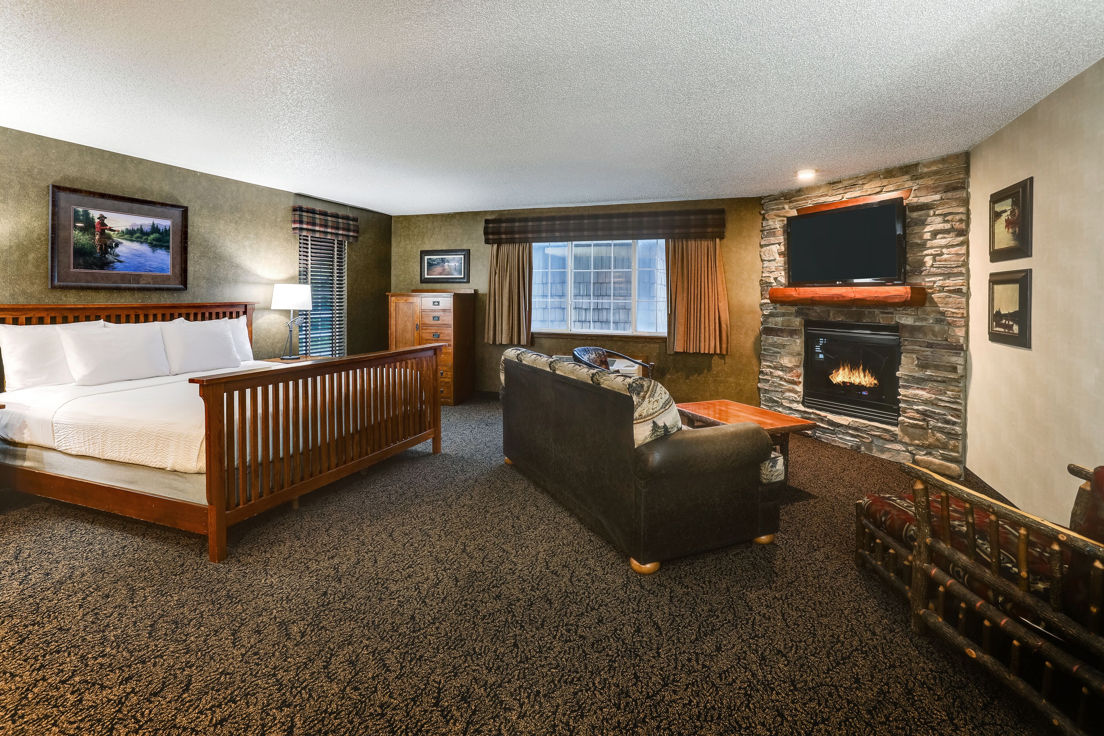 Quarto de hotel com cama, sofá, lareira e televisão.