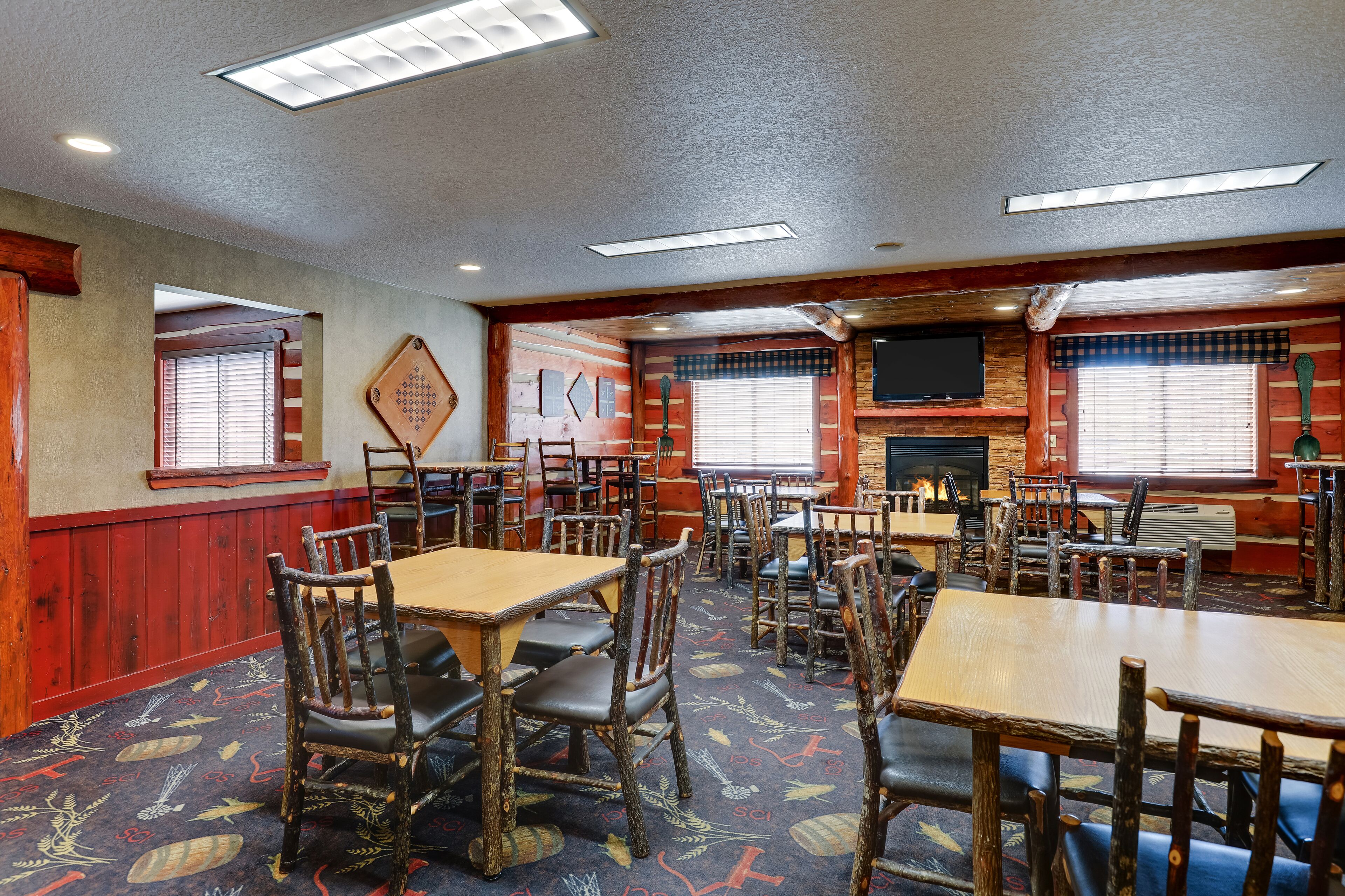 A dining area with wooden tables and chairs, a fireplace, and a television mounted on the wall.