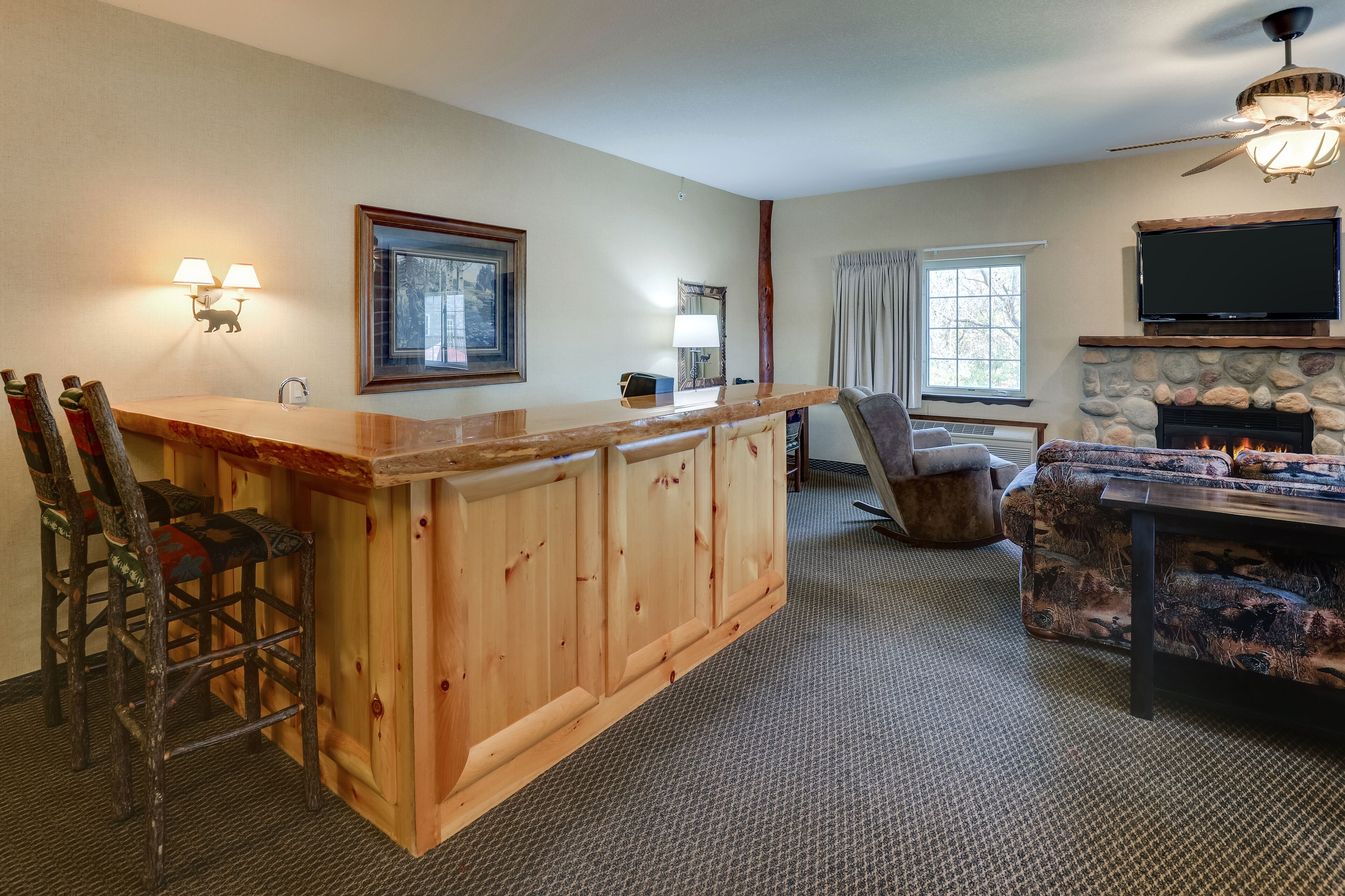 Un salon chaleureux avec un bar en bois, une cheminée, un téléviseur et un coin salon confortable.