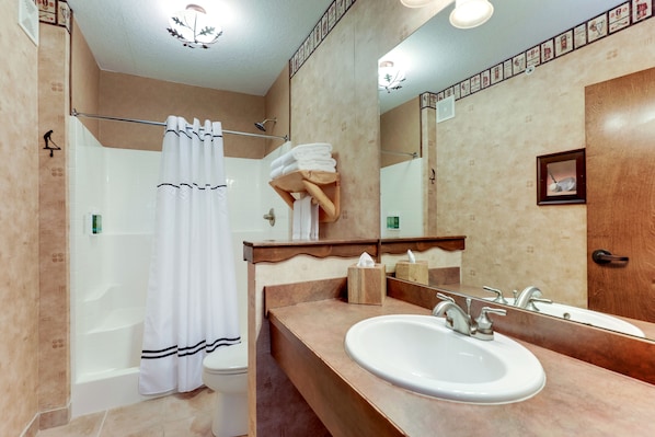 Un baño con bañera, ducha y lavamanos con espejo.