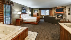 Una habitación de hotel con una cama grande, chimenea, televisor y jacuzzi.