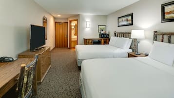 A hotel room with two beds, a desk, a television, and a coffee machine.