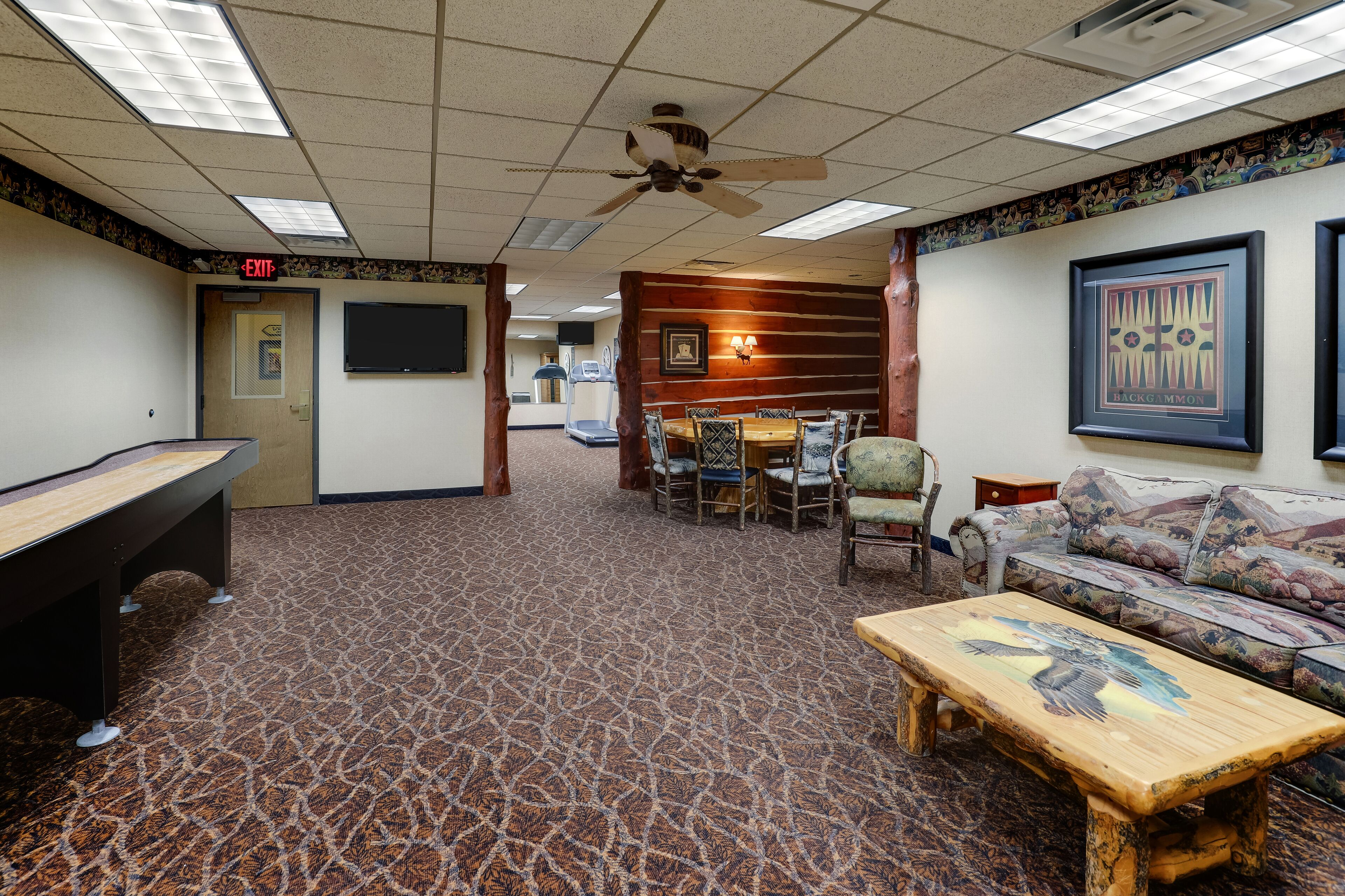 A room with a pool table, a sofa, a wooden coffee table, and a ceiling fan.