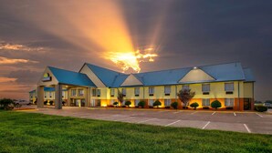 Days Inn -hotelli, jossa on parkkipaikka ja taivaalla myrskyää.