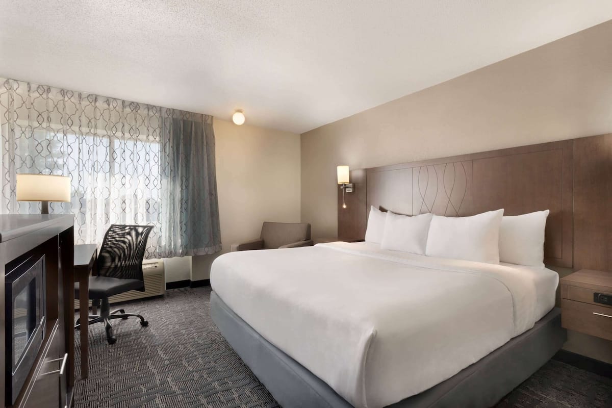 Une chambre d’hôtel avec un grand lit, un bureau avec une lampe, une chaise et une table de chevet.