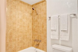 Un baño con ducha, inodoro y toallero.