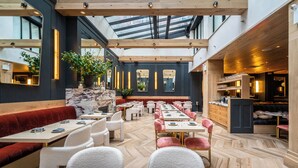 A modern restaurant with a high ceiling, wooden beams, and a mix of seating including booths and tables. - Hotel On Rivington (New York)