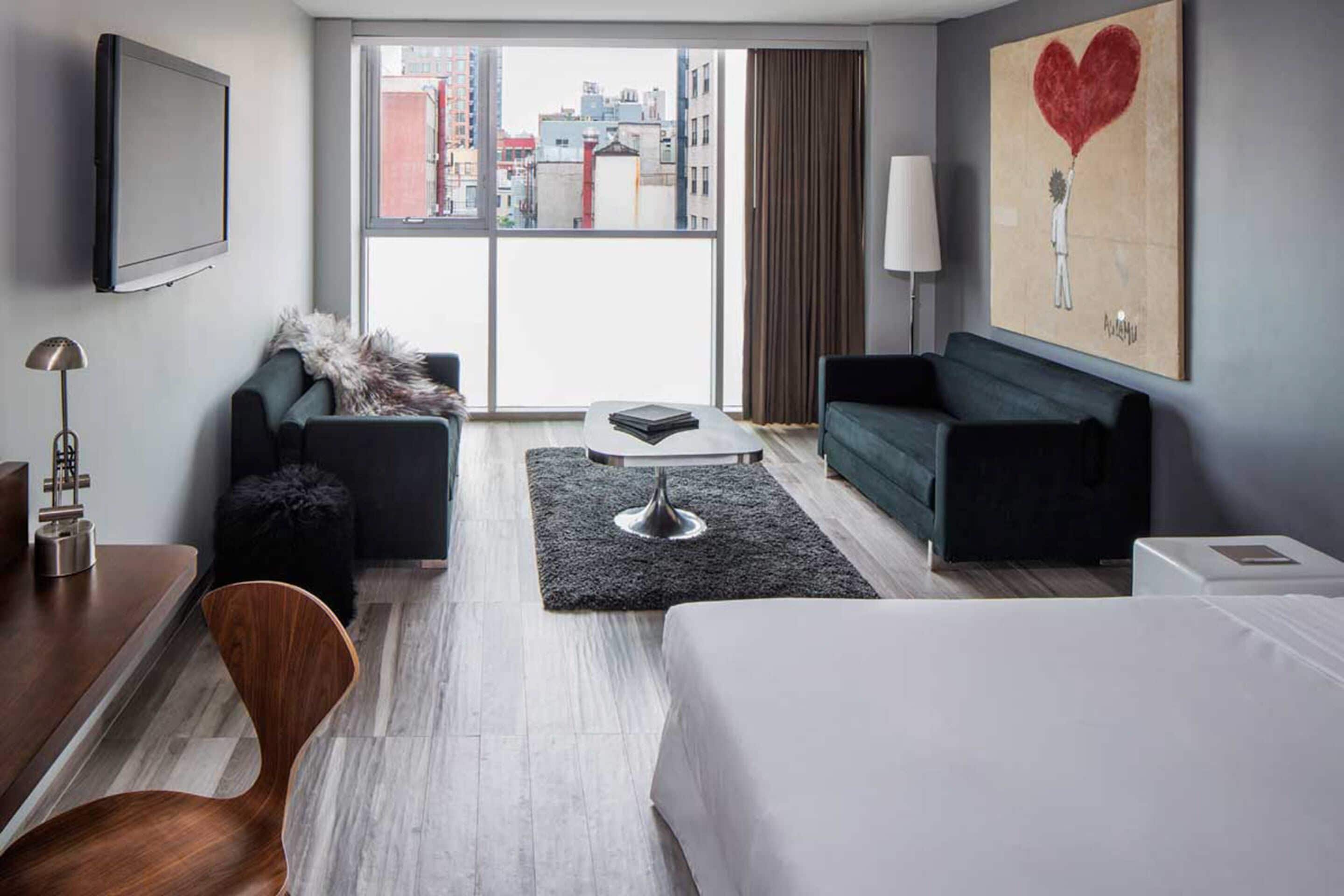 Une chambre d’hôtel moderne équipée d’un lit, de deux canapés, d’une table basse et d’un téléviseur.
