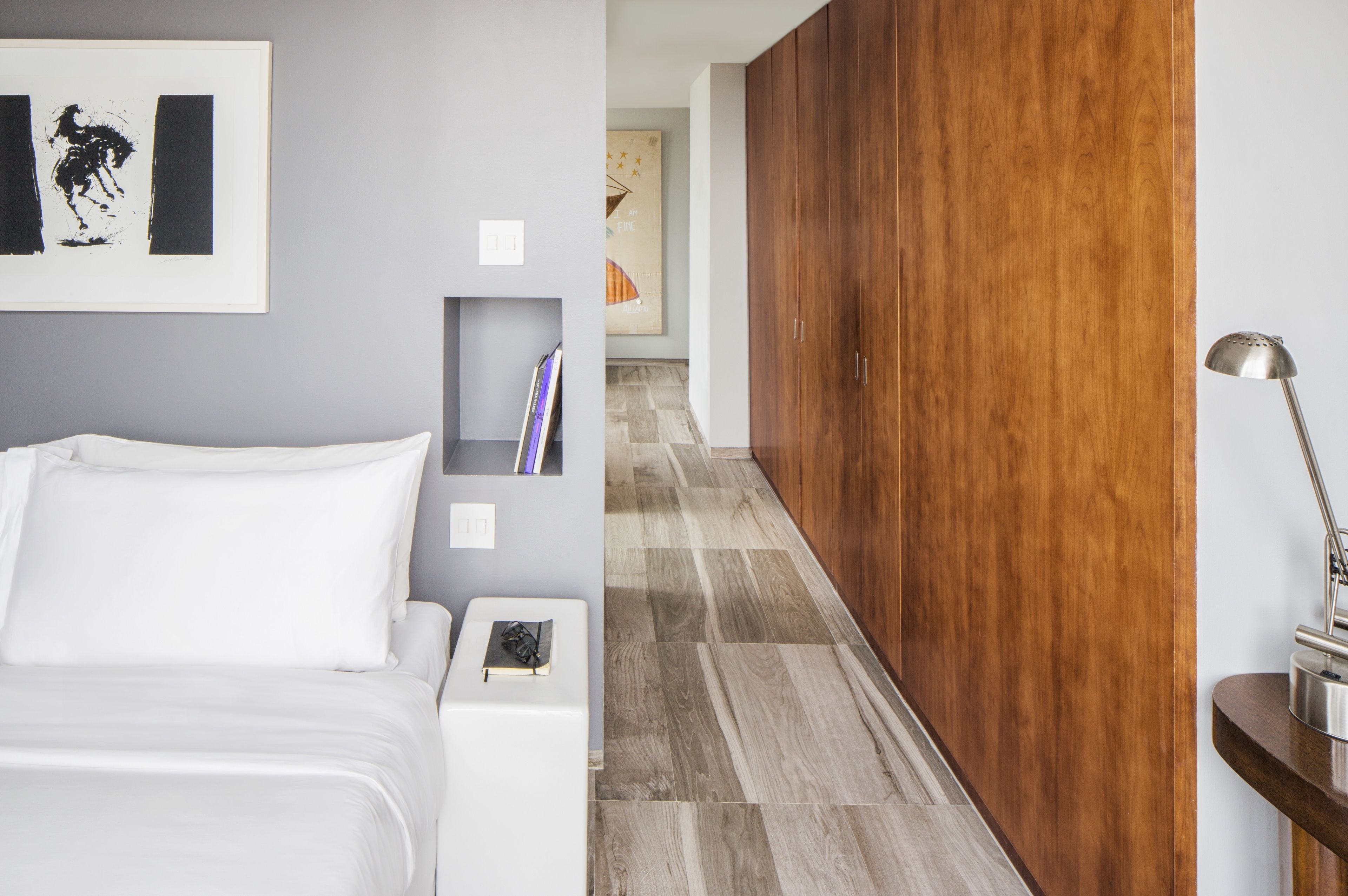 A hotel room with a bed, a nightstand, a bookshelf, and a wooden wardrobe.