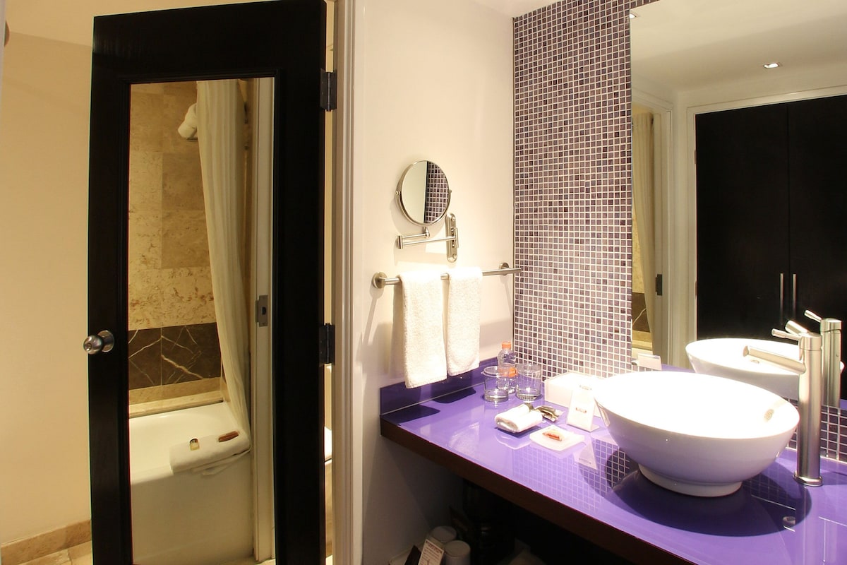 A bathroom with a bathtub, a sink with a mirror, and a towel rack.