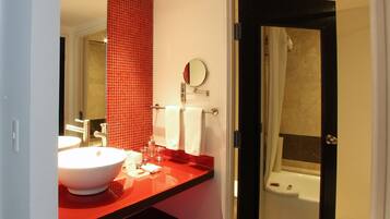 A bathroom with a red tiled wall, a white sink, and a bathtub.