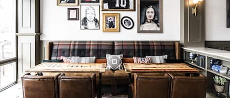 A dining area with a wooden table, four leather chairs, a plaid sofa, and a patterned rug.