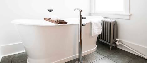 Un baño moderno con una bañera independiente, un perchero y un radiador.
