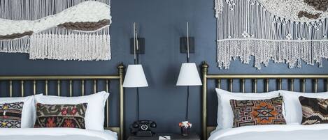 Een hotelkamer met twee bedden, een nachtkastje met telefoon en decoratie aan de muur.