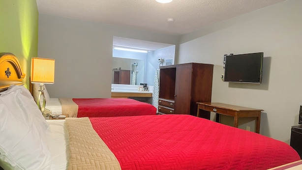 A hotel room with two beds, a TV, a mirror, a wardrobe, and a desk.