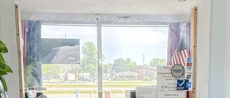 A window with a view of a parking lot and buildings, a welcome sign, and a credit card machine.