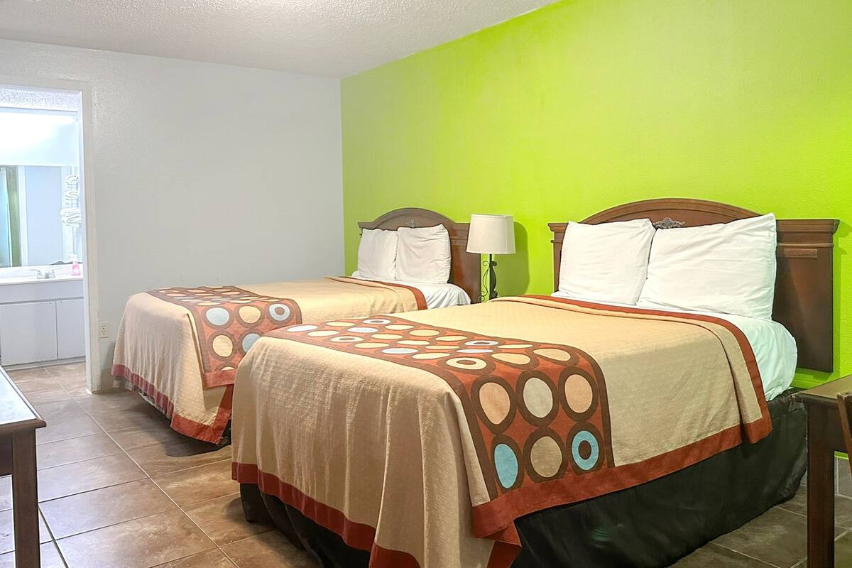 Une chambre d’hôtel avec deux lits, une fenêtre et un mur vert.