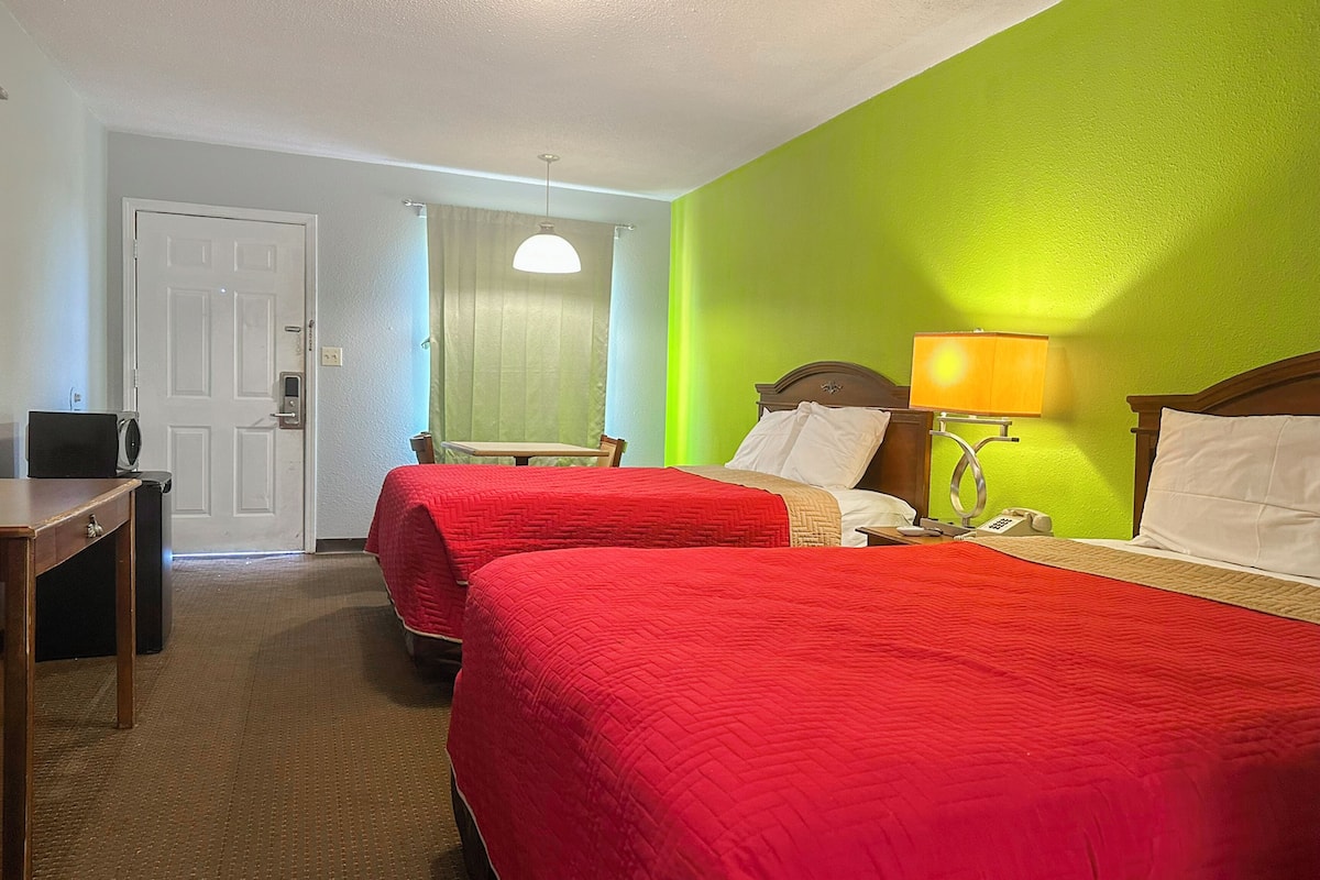 Une chambre d’hôtel avec deux lits, un bureau, une lampe et un téléphone.