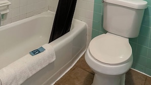 A bathroom with a bathtub, toilet, and a shower curtain.