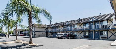 A motel with a two-story structure, a parking lot, and a palm tree.