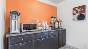 Una kitchenette equipada con cafetera, microondas y dispensadores de café.