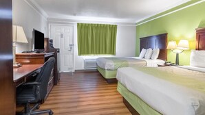 Habitación de hotel con escritorio, dos camas, una silla, televisor y ventana con cortinas.