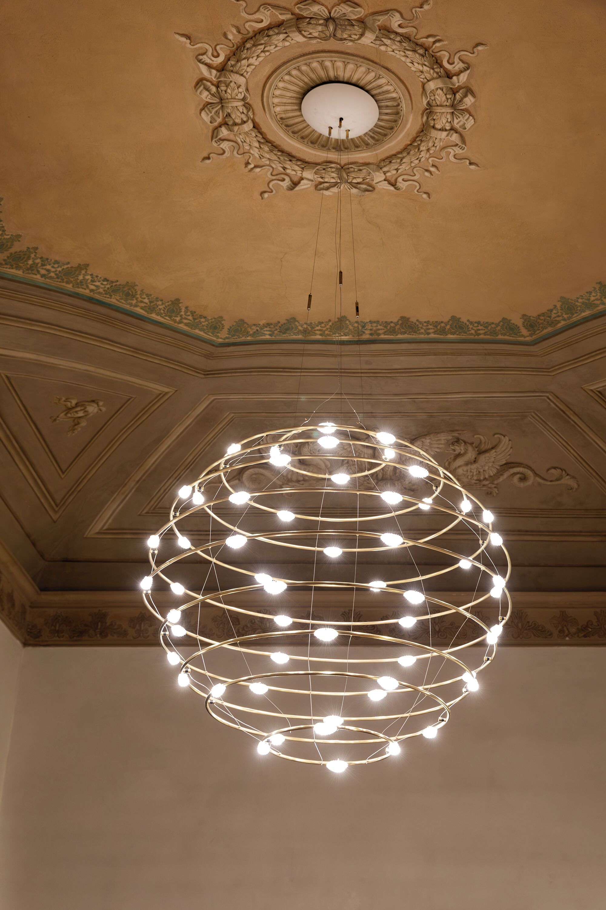 A ceiling with a decorative circular design and a spherical light fixture.