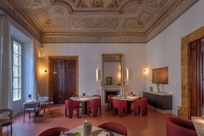 A dining area with red chairs, a fireplace, and a large mirror.