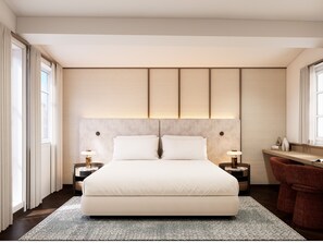 A modern bedroom with a large bed, bedside tables, a desk, and a chair.
