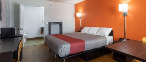 Hotellihuone, jossa on sänky, työpöytä, tuoli ja pieni pöytä.