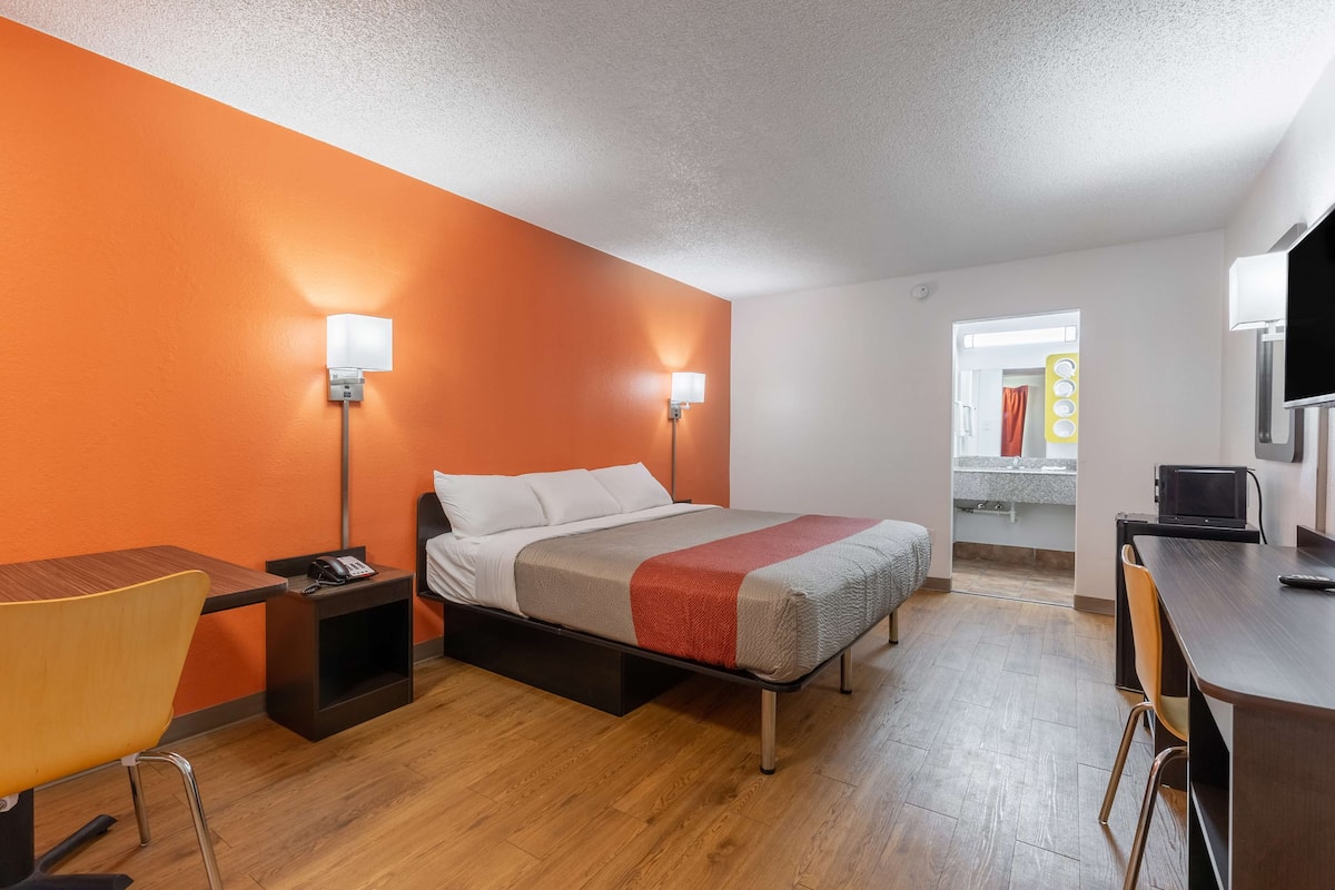 A hotel room with a bed, bedside tables, a desk, and a chair.