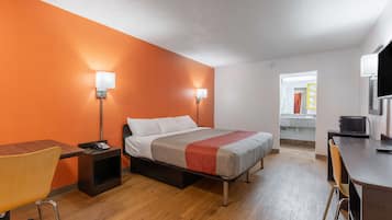 A hotel room with a bed, bedside tables, a desk, and a chair.