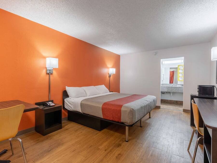 A hotel room with a bed, bedside tables, a desk, and a chair.