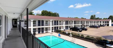 A motel with a swimming pool, a covered walkway, and a parking lot.