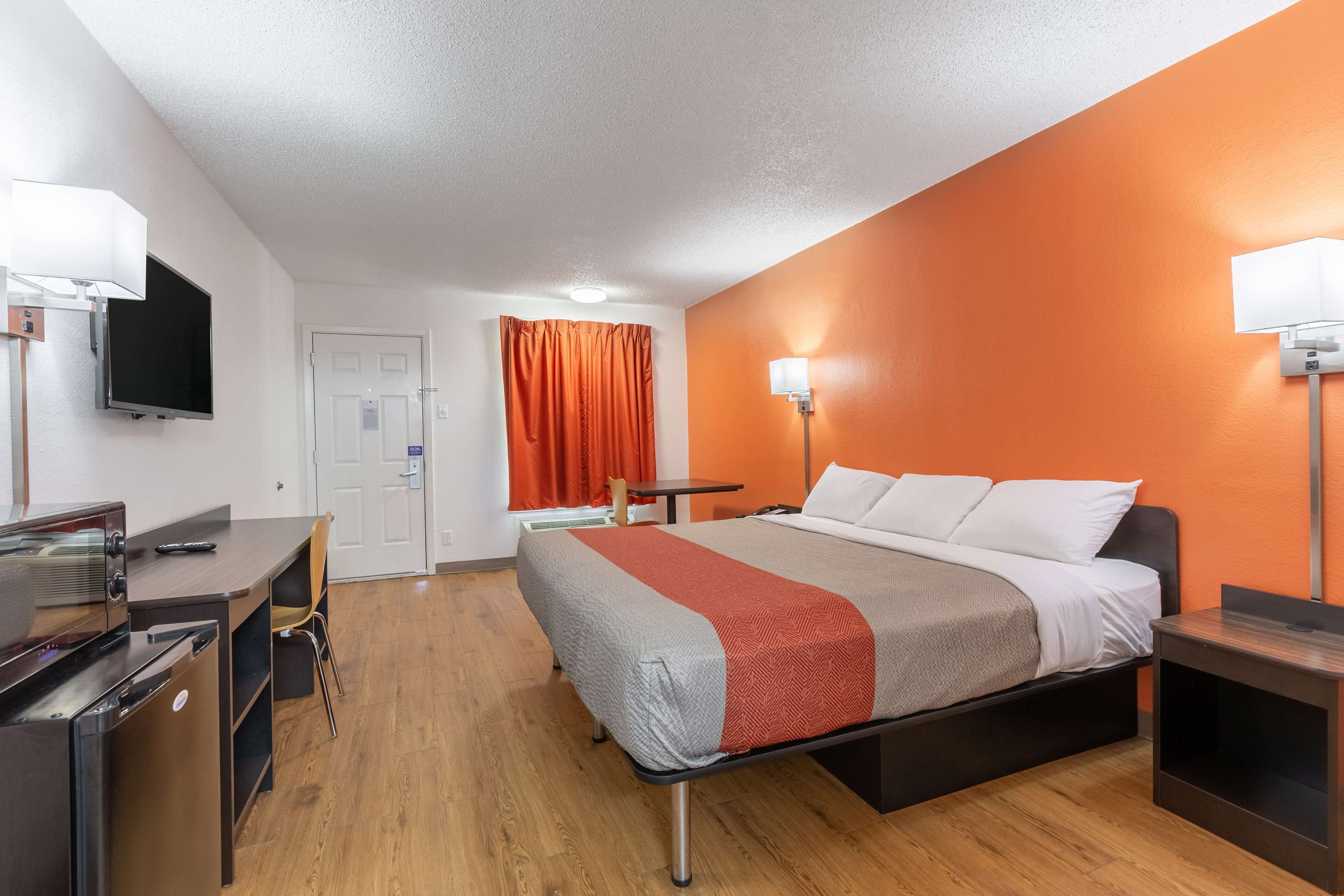 Una habitación de hotel con cama, escritorio, silla y televisión.