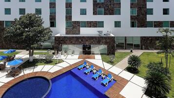 Un hotel con piscina, mobiliario exterior y fachada de edificio moderna.