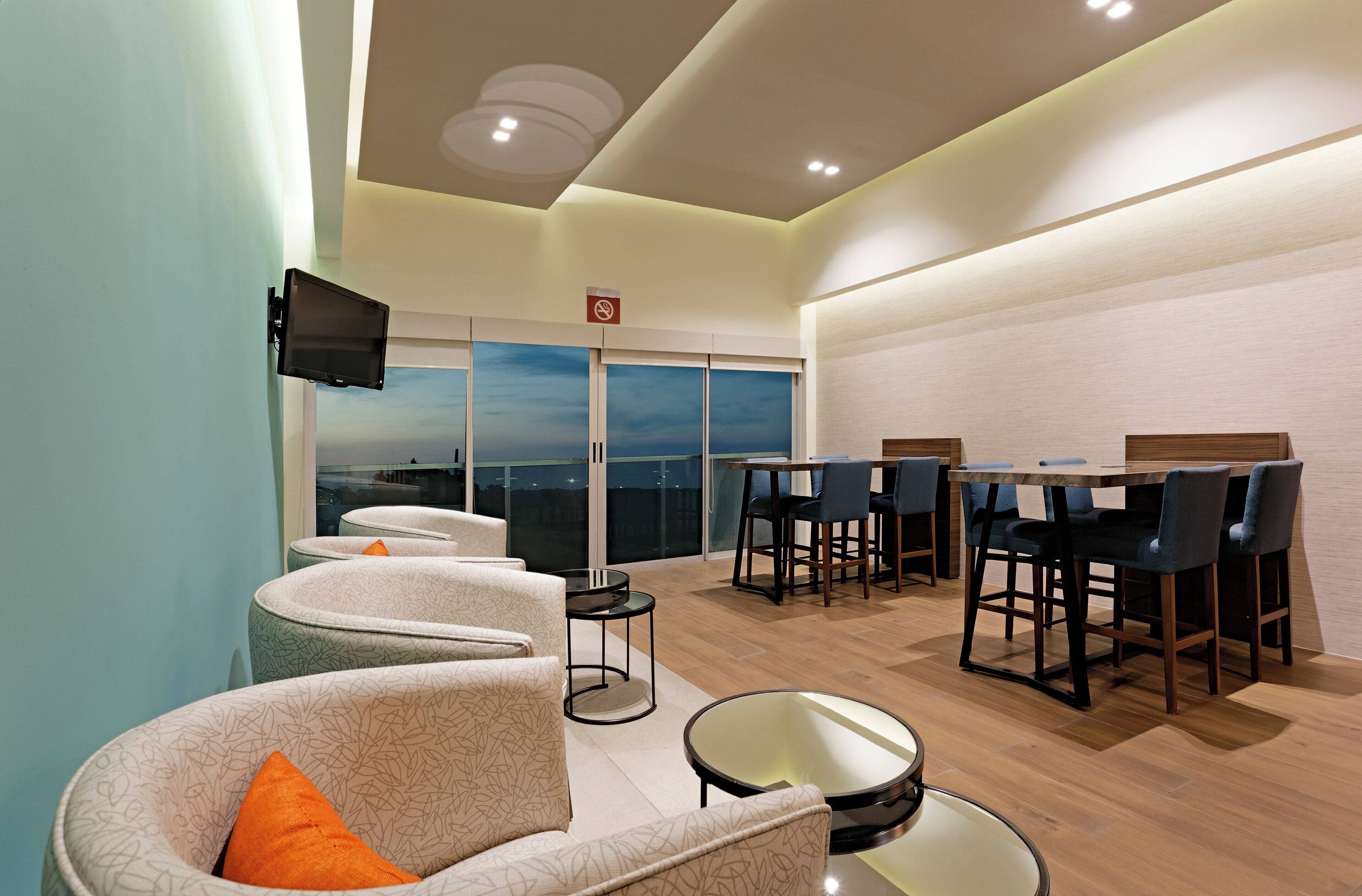 Un área de estar moderna con asientos, una mesa de comedor y un ventanal con vistas a la ciudad.