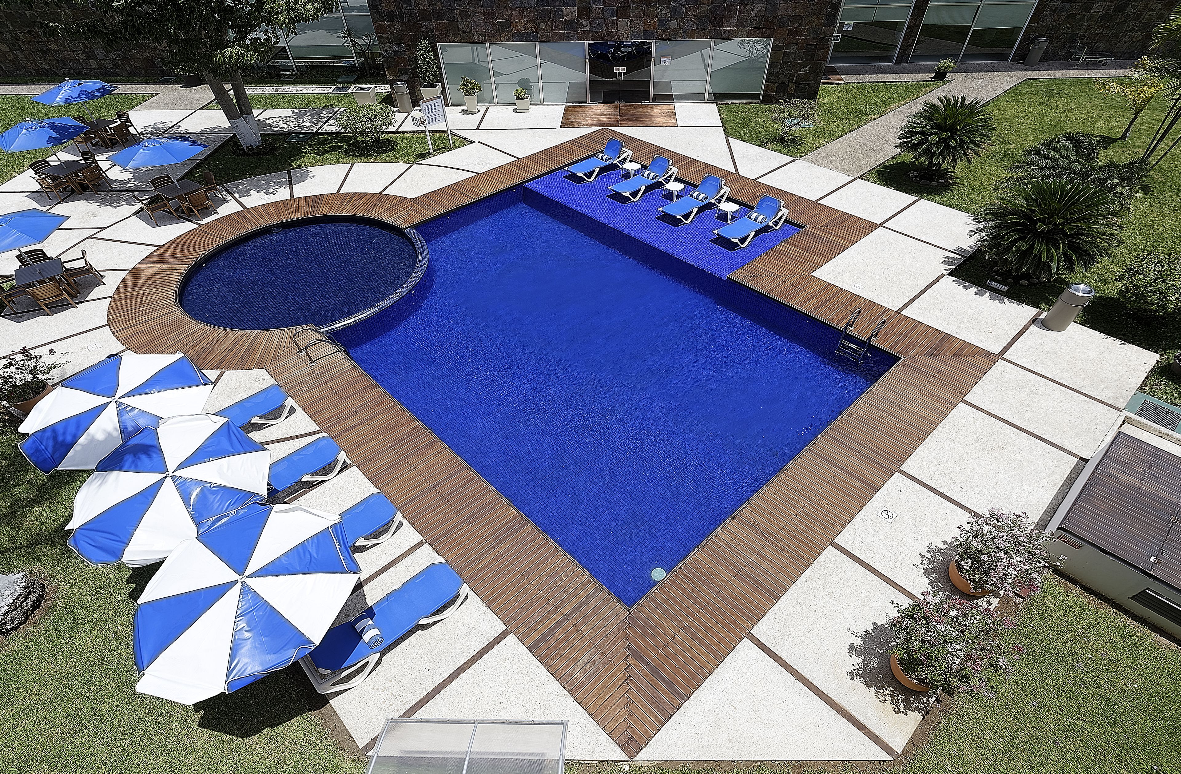 Een buitenzwembad, parasols bij het zwembad en ligstoelen