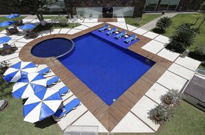 Alberca al aire libre, sombrillas en la alberca y camastros