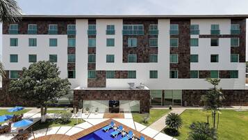 Un hotel moderno con zona de piscina, mobiliario exterior y fachada de piedra y blanco.