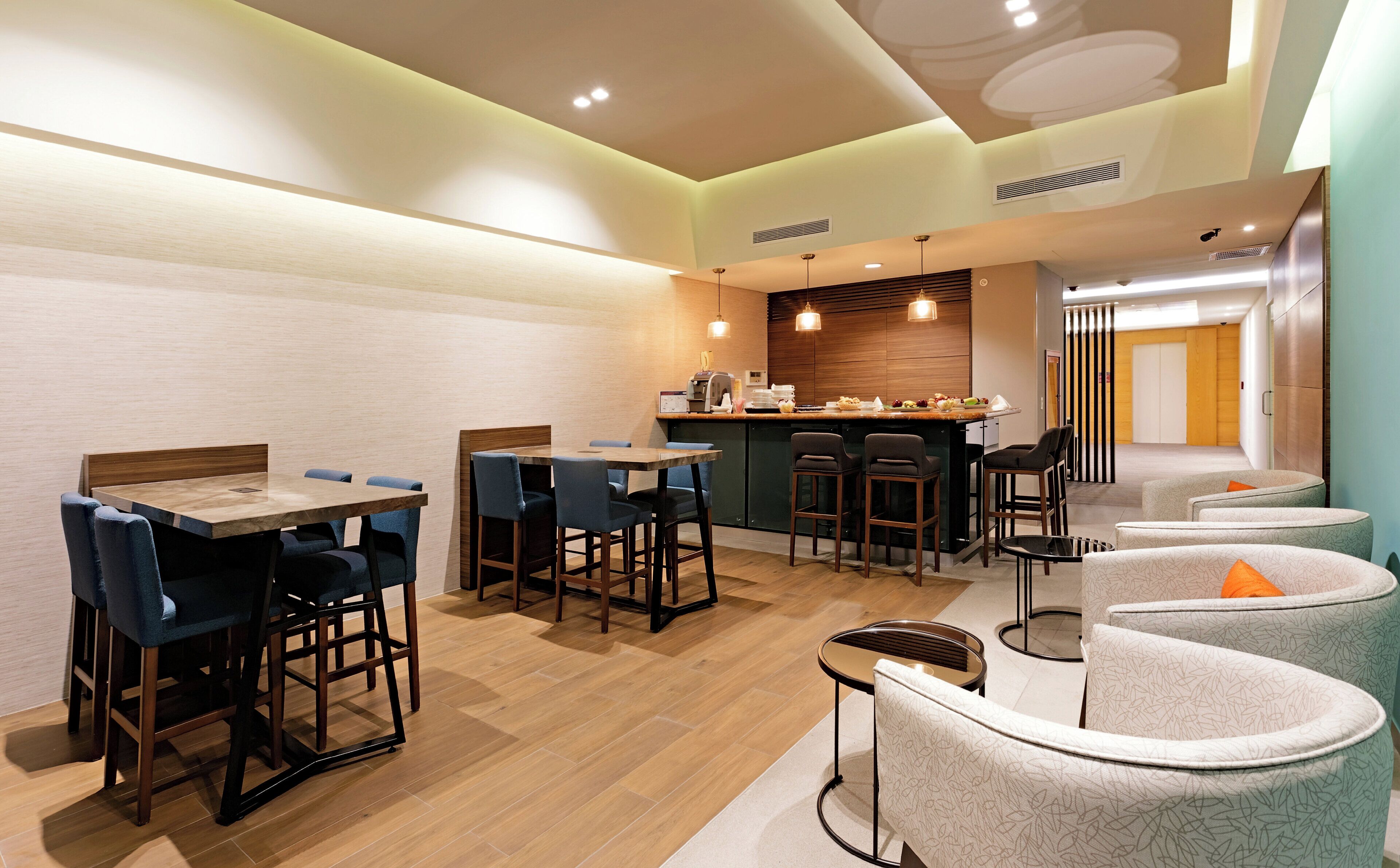 A modern restaurant with a bar area, seating arrangements, and a kitchen visible in the background.