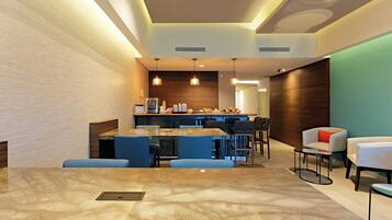 A modern hotel lobby with a marble floor, a bar area, and seating arrangements.