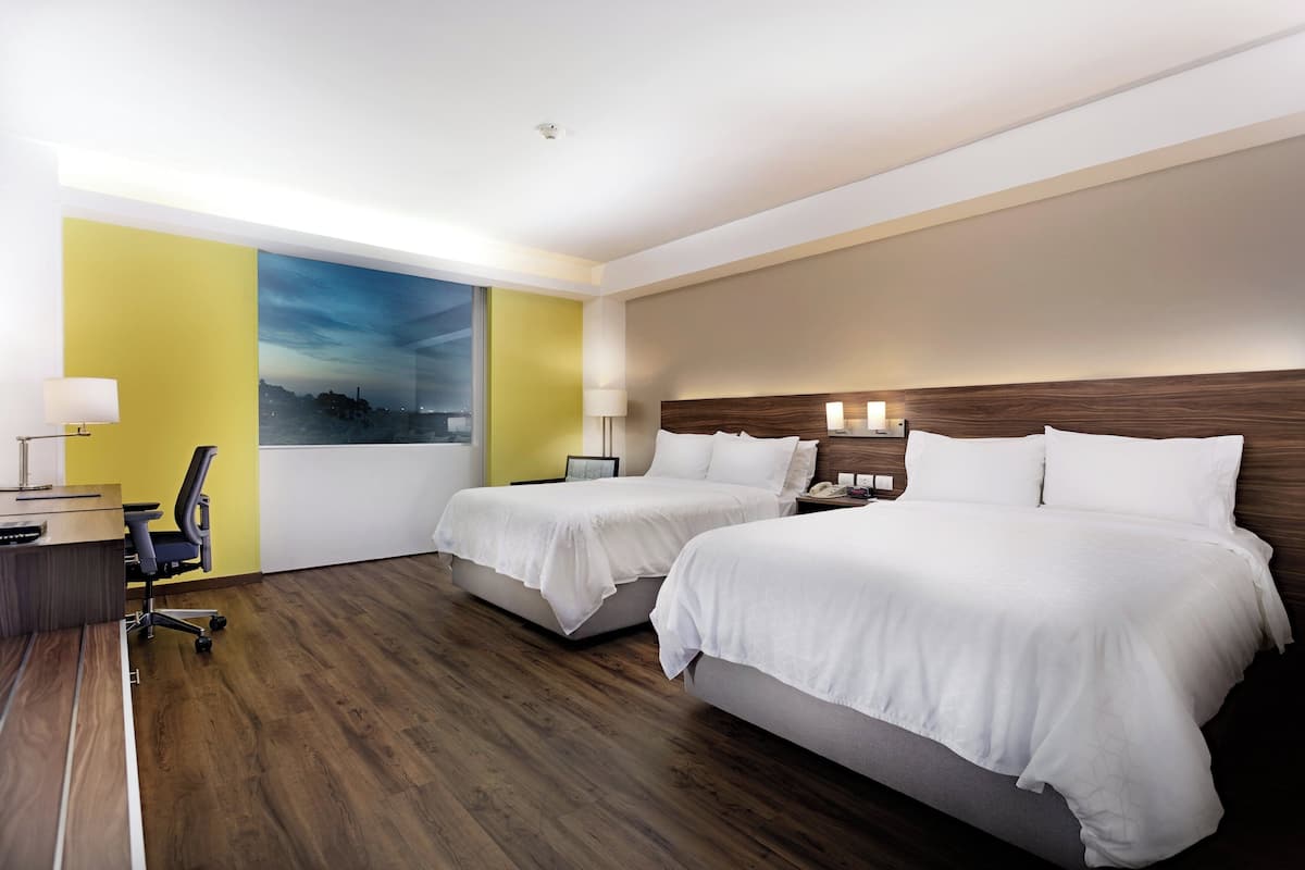 Une chambre d’hôtel avec deux lits, un bureau et une chaise.