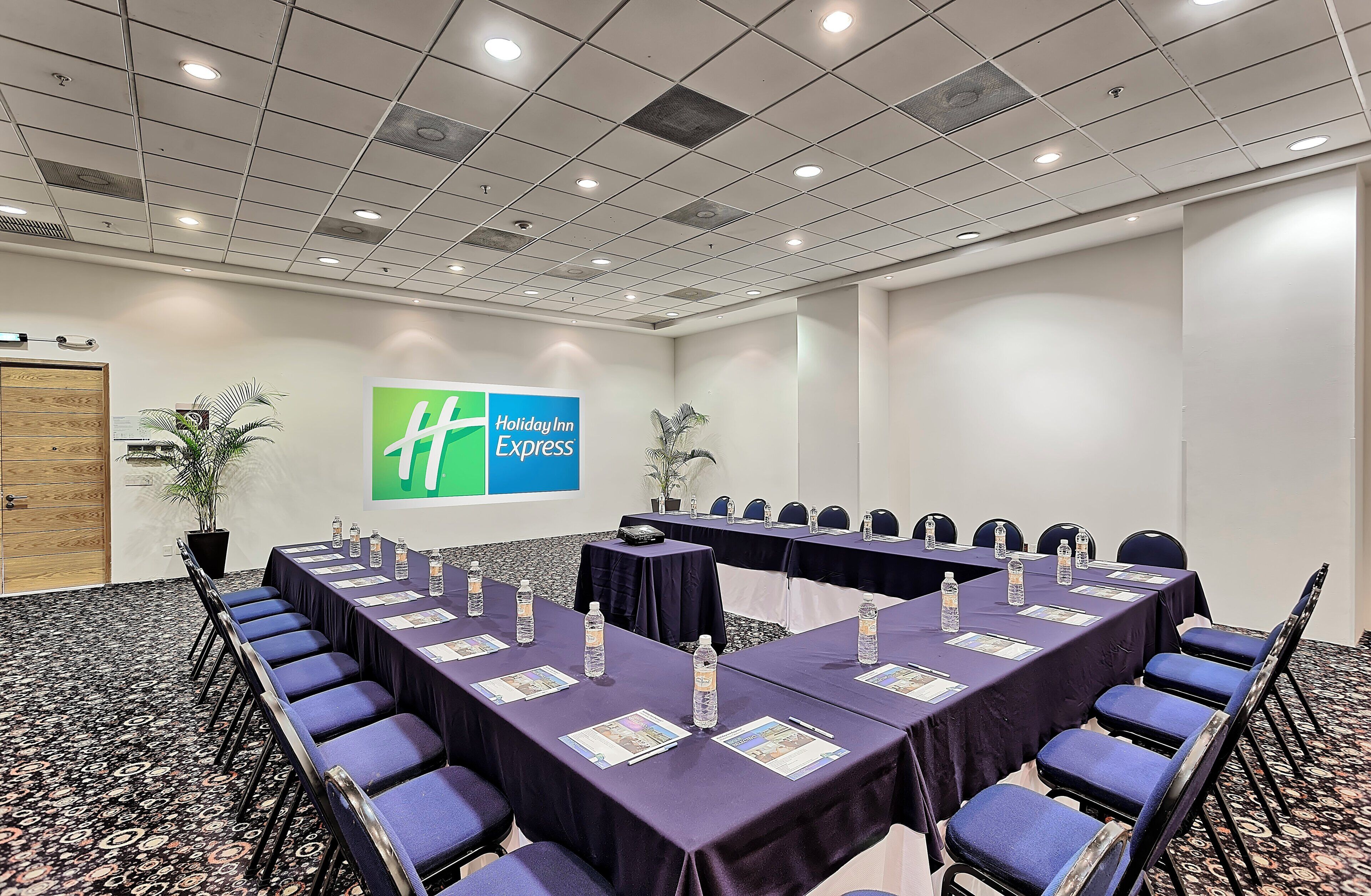 Un salón de conferencias con una larga mesa, sillas y un letrero de Holiday Inn Express en la pared.