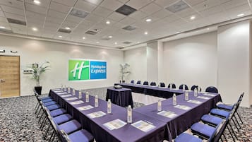 Un salón de conferencias con una larga mesa, sillas y un letrero de Holiday Inn Express en la pared.